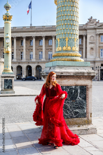Foto Elegant fashion influencer Greta Gardner (Ivana Benko) wearing a luxurious long red tulle dress at Place de la Concorde in Paris, posing in front of a majestic historical monument under a blue sky