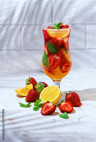 Fotografie Refreshing soft drink with strawberries, lemon and mint, on a light background,