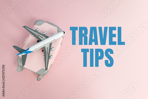 Airplane model on a suitcase with travel tips text on a pastel background. Concept of travel advice, tourism planning, vacation preparation and trip guidance.