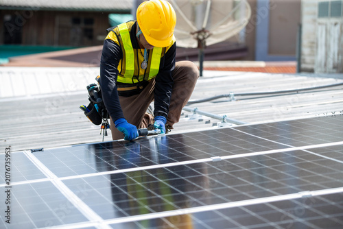 Fotografie Solar Panel Installation: A worker in safety gear meticulously installs solar panels on a rooftop, contributing to sustainable energy solutions and a greener future