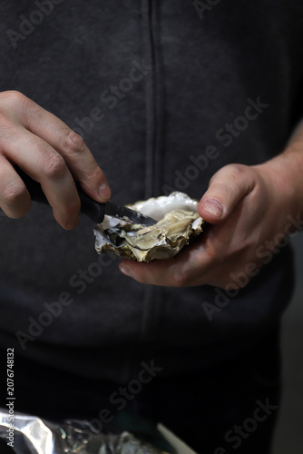 Tableau sur toile experto abridor de ostras abriendo una ostra con sus manos y un cuchillo especia