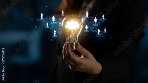 Business concept of networking and connections with glowing light bulb and digital icons of people over dark background, symbolizing bright ideas and collaborative growth. Entropy.