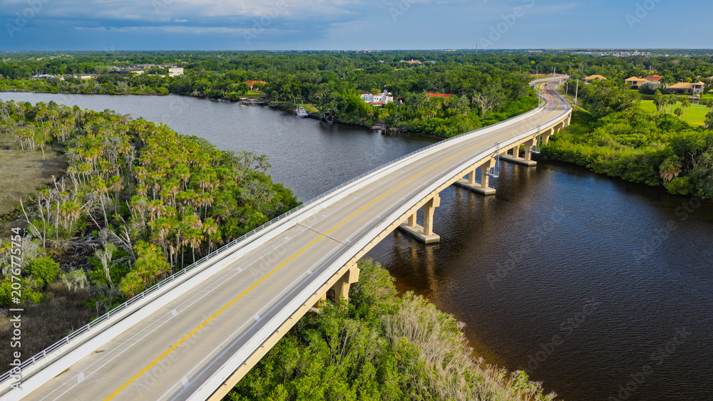 Fototapeta premium An aerial view of the Fort Hamer Bridge over the Manatee River in Bradenton, Florida. Afternoon rain showers fill the dark sky in the distance.