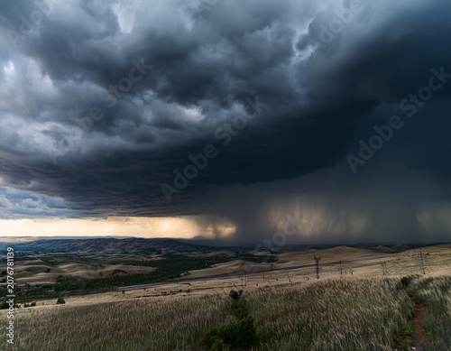 dark stormy heavens looming over a broad landscape delivering heavy precipitation
