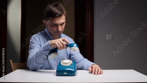 Vászonkép Man holding an old turquoise rotary telephone receiver, waiting to connect on a