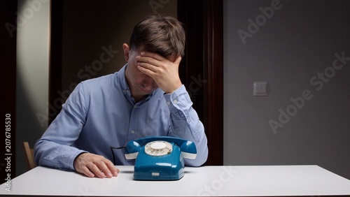 Cuadro en lienzo Anxious man covering his face with his hand while sitting patiently at a table