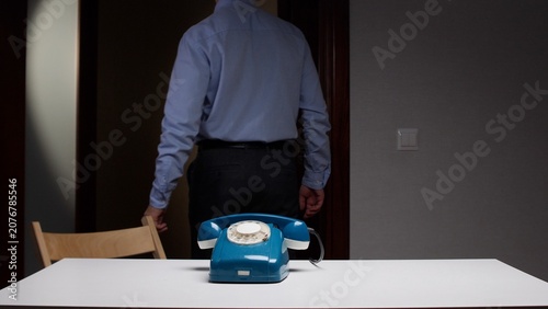 Fotografie Man in a blue shirt and dark trousers walking away, leaving a vintage blue rotar