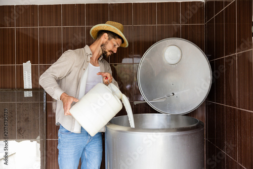 Konstfotografi Dairy farmer in straw hat pouring fresh milk from a canister into a stainless st