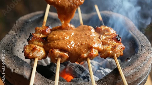Close-Up Shot Of Indonesian Chicken Satay Skewers Drizzled With Peanut Sauce On Charcoal Grill Background