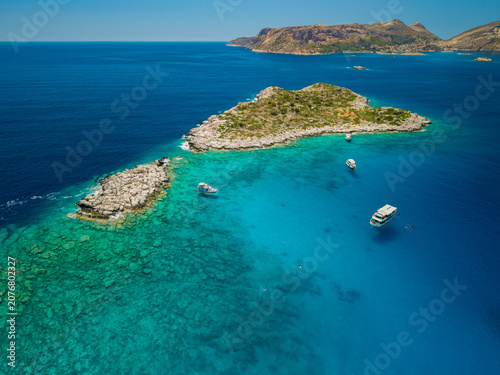 Aerial view of tour boats floating on turquoise water near rocky islands in Kas Antalya.