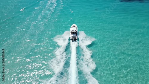 Speedboat wake in clear turquoise tropical ocean water.