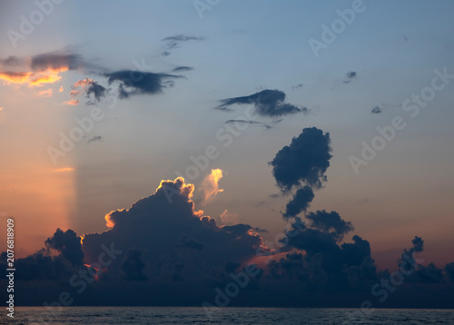 Canvas Print Sun setting behind dark clouds with dramatic golden crepuscular light rays