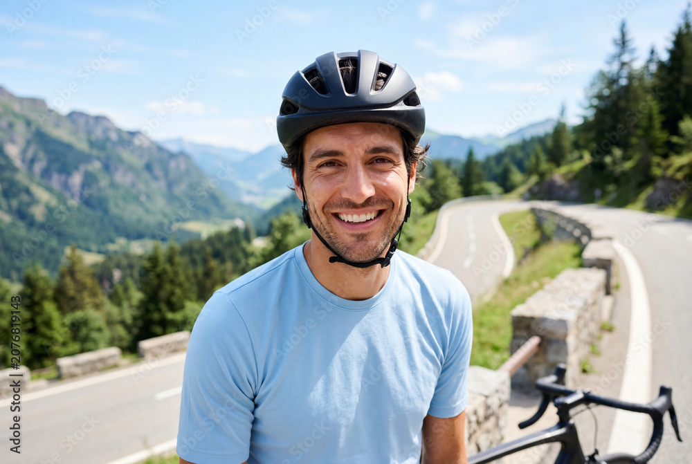 Fototapeta premium Smiling male cyclist in a helmet on a winding mountain road