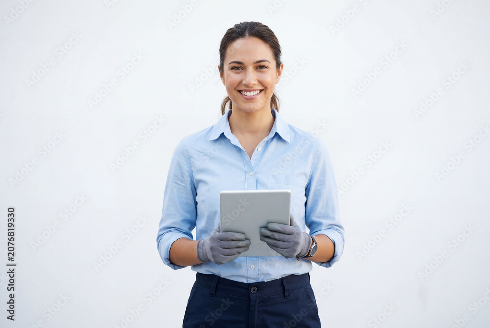 Obraz premium Smiling female electrician holding digital tablet against white wall