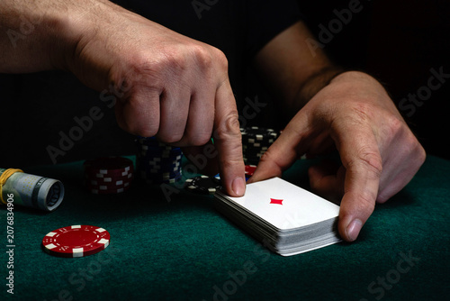 Fotografie Two hands are seen preparing a stack of cards on a green table