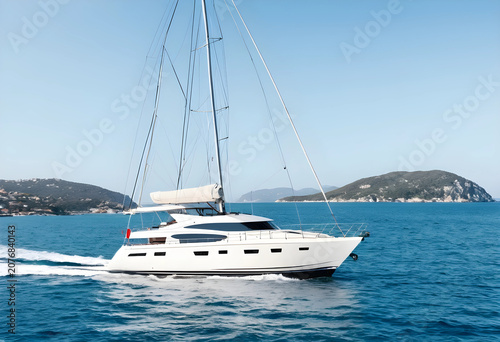 White yacht sailing on blue sea near coastal islands