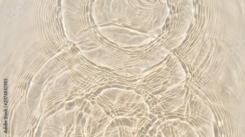 Clear water surface with gentle circular ripples and bright sunlight reflections creating a peaceful and calming natural abstract texture pattern