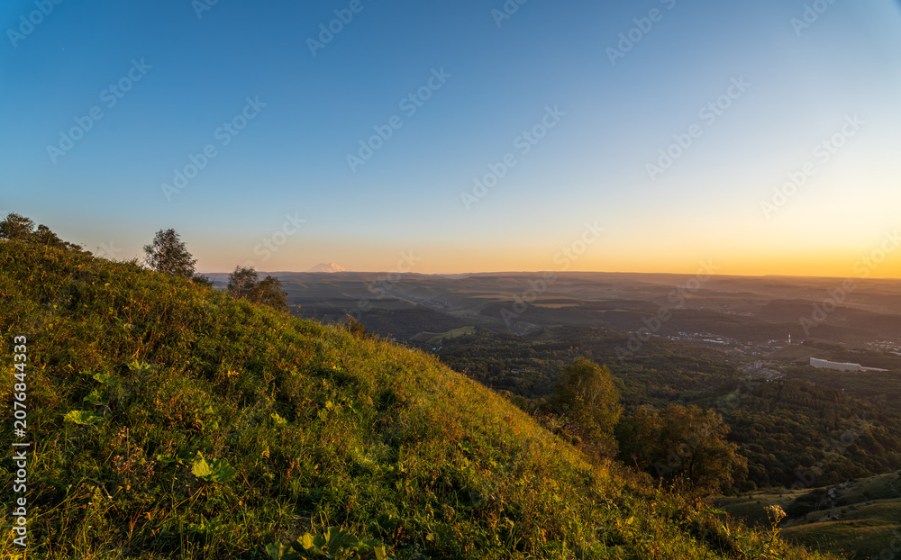 Fototapeta premium Layers of green mountains and hills in the haze during sunset. Panoramic View of Green hills and Meadow.