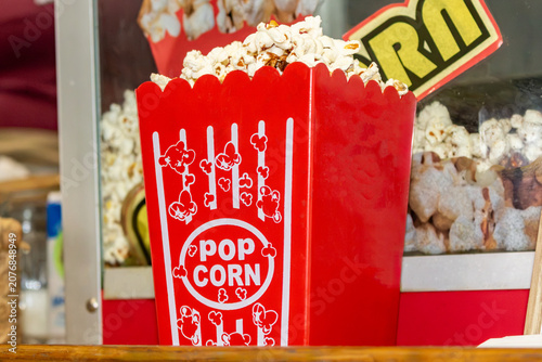 Saco de pipoca vermelho cheio de pipoca doce e fresca em máquina de pipoca