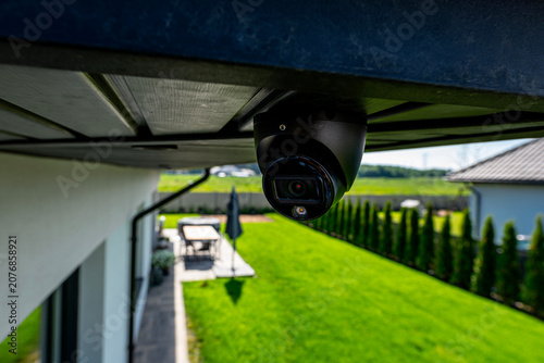 Dome security camera monitoring modern home backyard
