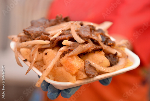 Brazilian Carne de Sol with Cassava and Onions Served in a Food Container.