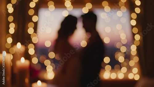 Romantic couple silhouette blurred with warm bokeh fairy lights.
