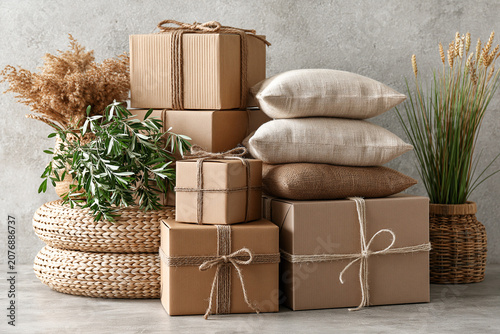 Stacked cardboard gift boxes and linen pillows with dried decor