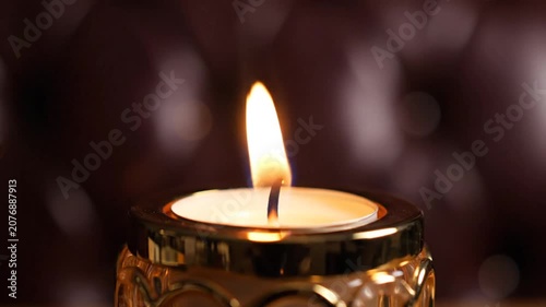Single lit candle flame in an ornate glass holder.