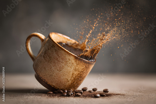 Coffee spills from cup on table with coffee beans scattered around during morning light