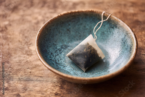 Tea bag placed on a small blue dish after brewing in a kitchen setting
