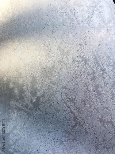 Frost patterns on window glass on a snowy day, winter texture background