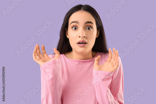 Scared young woman on lilac...
