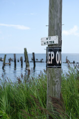 No litter and keep out signs on post with bay and dock pilings