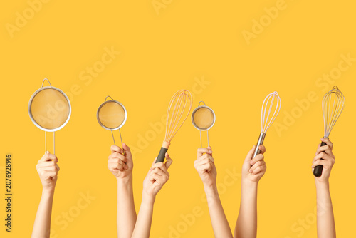 Schilderij op canvas Female hands with sieves and whisks on yellow background