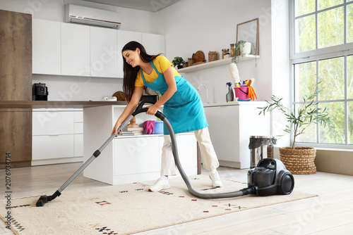Young woman vacuuming carpe...