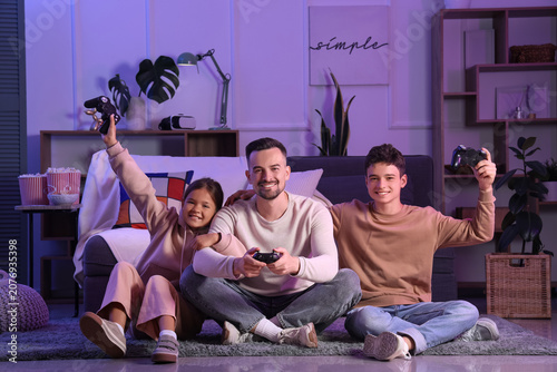 Father with his children playing video game at home in evening
