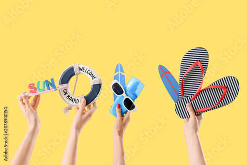 Tableau sur toile Female hands with beach accessories and word SUN on yellow background