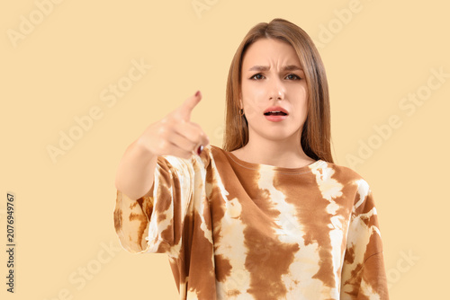 Fotografía Young woman pointing at viewer on beige background, closeup