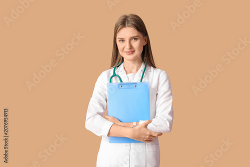 Beautiful young doctor on beige background
