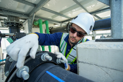 Engineer maintenance hvac cooling tower technician safety inspection at plant with hard hat glove and reflective vest working on large pipe and flange focused service ensures climate control