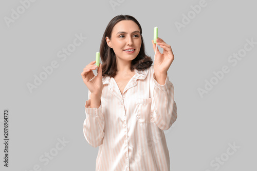 Beautiful young woman with tampons on grey background
