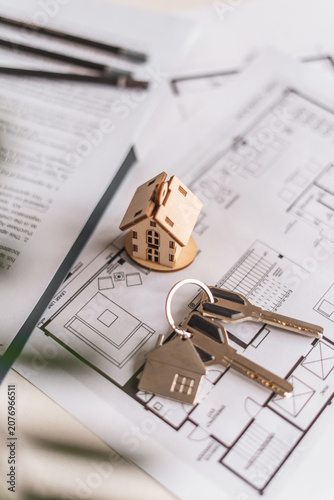 House model, keys and floor plans create visual representation of selecting ideal residence. Concept of architectural planning, smart investment and personalized housing decisions.