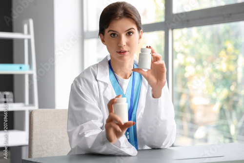 Female doctor with pill bottles video chatting in office