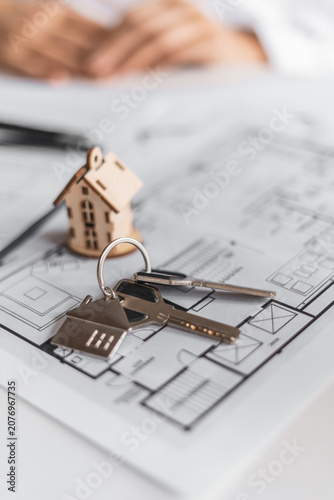 Miniature house and keys displayed above contract papers symbolize mortgage approval and residential financing. Professional consultation helps clients secure ideal property solutions.