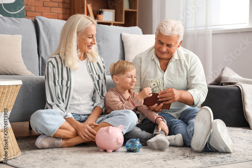 Obraz na płótnie Little boy with his grandparents taking money from wallet at home