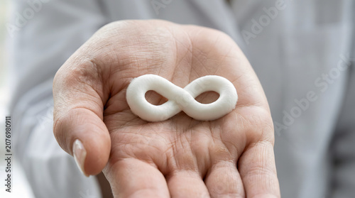 Infinity symbol, a white, smooth, abstract shape representing endlessness, eternity, and limitless potential, held delicately in a person's open palm, symbolizing concepts of forever, continuity