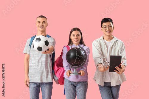 Happy students with soccer ball, globe and molecular model on pink background