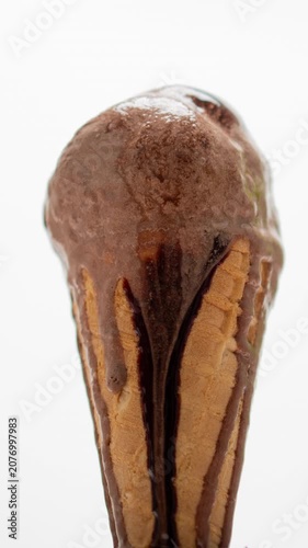 4K Time lapse Close-up delicious chocolate ice cream cone topped with rich chocolate syrup melting down the waffle cone isolated on white background.