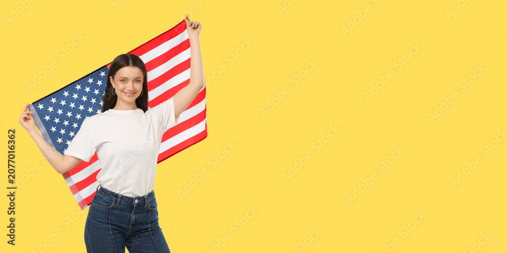 Fototapeta premium Woman waves American flag joyfully. Celebration and travel concept in bright yellow space