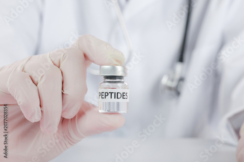 Fotografie Confident doctor wearing glove holding peptide vial inside wellness clinic showc